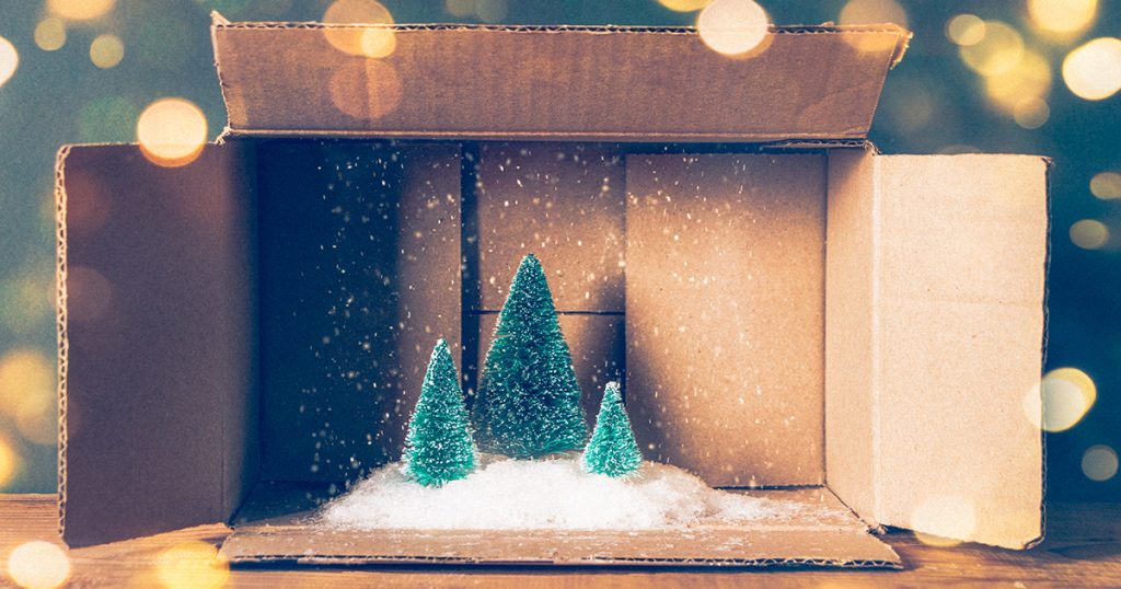 Miniature of Christmas trees with snow in a cardboard box. Lights bokeh and film grain added.